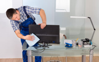 Male Janitor Cleaning Computer In Office